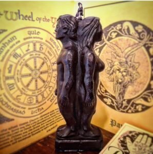 candela a forma diuomo e donna nere di spalle su sfondo giallo con simboli esoterici